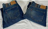 Two folded pairs of Levi's 541 denim jeans showing back pockets, red Levi's tabs, and tan leather brand patches on waistband.
