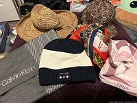 Overview of the hats and scarves laid out including woven and bucket hats, knit beanies, and various scarves.