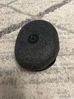 Closed hard shell carrying case with Beats logo on top, placed on carpeted floor.