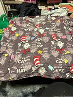 Front spread of nurse scrub top showing repeated Cat In The Hat print on gray fabric.