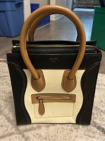 Front exterior view showing black, cream and brown pebbled leather panels, Celine Paris logo and front zip pocket.