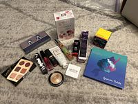 Photo showing full contents of the lot including palettes, perfume box, nail polishes, mascaras, and other cosmetics.