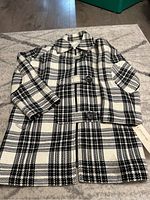 Full front view of the black and cream plaid Jones New York peacoat laid flat, showing double-breasted buttons and collar.