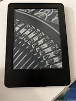 Front view of Amazon Kindle eReader showing a close-up of the E-ink display with vintage typewriter keys screensaver.