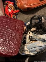 Photo showing a large brown leather-like travel makeup case, a dark burgundy crocodile textured purse, and multiple other purses in a bag.