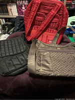 Three Lug totes displayed together: red quilted backpack style, black quilted tote, and grey tote with woven pattern