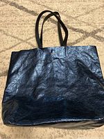Front view of a large sapphire blue tote bag with two black handles.