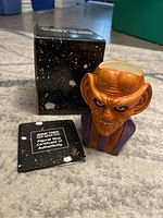Star Trek Quark figural mug, original black box with space design and Certificate of Authenticity booklet shown on carpeted floor.