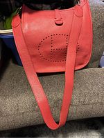Front view of red pebbled leather bag with long strap draped