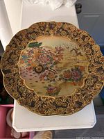 Full view of the round Satsuma plate showing scalloped edges and intricate border design with gold leaf.