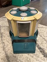 Front view of Star Trek Playmates transporter toy showing missing door and transparent window, teal base with cream accents