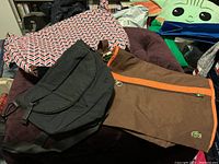 Lot of three totes: black Lululemon shoulder bag on left, brown Lacoste bag in middle, and larger patterned tote on top