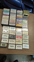 Overview of entire cassette tape collection laid out on table, approximately 45 tapes visible.