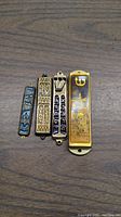 Four mezuzahs on a wooden surface, each with Hebrew inscriptions and traditional Jewish symbols.