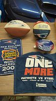 Four New England Patriots sports memorabilia items and a banner on a table, showing logos, team colors, and text.