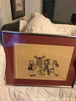 Framed print titled 'Benchmark' showing four children in various poses, mounted on a red mat and set in a silver-tone frame.