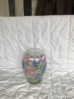 Front view of the glass vase showing hand painted floral design in pink, blue, purple, with green leaves.