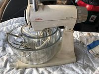 Sunbeam Mixmaster stand mixer with glass mixing bowl, metal beaters, and power cord.