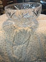 Clear vintage footed crystal bowl placed on a patterned cloth, showing cut glass detailing and footed base