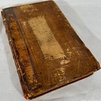 Front cover of the leather-bound book showing wear, scratches, and loose cover condition.