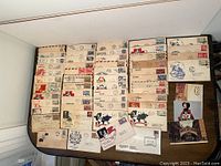Wide view of a large assortment of vintage first day covers laid out on a table showing multiple rows and designs.