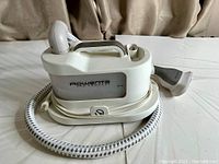 Rowenta IS1430 Pro Compact garment steamer shown with main body, cord wrapped around base, and flexible hose attached.