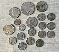 Top view of 19 vintage American circulated coins including Kennedy half dollars, Jefferson nickels, Washington quarters, Roosevelt dimes, Buffalo nickels, and Lincoln pennies on a textured surface.