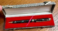 Pen displayed inside original box showing cloisonne enamel decorated body and gold-tone metal accents resting on red velvet lining.