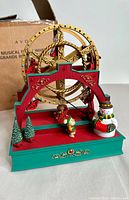 Front angle view of vintage Avon Ferris wheel Christmas decoration with snowman, bear, and trees on the base.