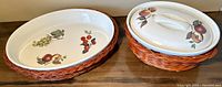 Two vintage porcelain serving wares with wicker baskets, one open oval dish and one with a lid, placed side by side on table