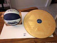 Top view of basketball and wooden balance board on table, basketball in box next to board