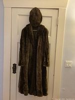 Full view of vintage beaver fur coat with matching hat hanging on a door, showing front side of coat.