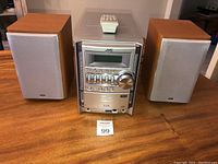 Front view of the JVC stereo system with speakers and remote control on a wooden table.