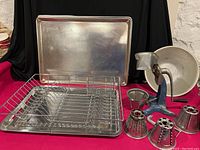 Retro WearEver manual rotary grater with blue cast iron base, black handle, enamel catching bowl, three metal cone-shaped interchangeable grater blades, two heavy-duty baking sheets, metal dish drainer and tray.