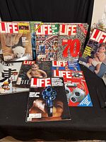 Full array of 12 magazines including 10 Life magazines and 2 Look magazines arranged in a group showing various colorful covers including a polar bear cub, gun, and babies.
