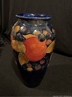 Front view of Moorcroft Pomegranate vase showing the large central pomegranate with leaves and berries on a deep blue background.