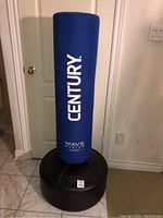 Full view of the Century Wave Master punching bag showing the blue cylindrical bag mounted on a black base.