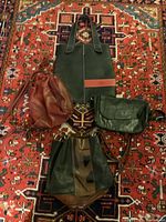 Four vintage purses displayed on a patterned rug: black and red TODS tote, black and brown textured handbag, brown slouchy handbag, dark green crossbody bag.