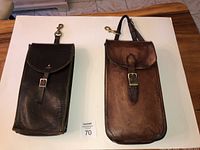 Two vintage leather saddle bags placed side by side on a table, showing front and overall condition
