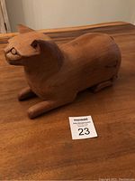 Front angle view of hand carved wooden cat box sitting on table showing the body shape and front legs.