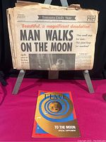 Full view of the newspaper folded open with bold front page headline about moon landing, alongside Time Magazine supplement cover showing the moon.