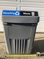 Front view of the large gray plastic bin with recycling and waste labels showing height measurement.