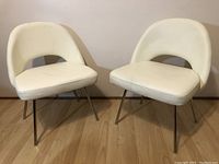 Front view of two white lounge chairs side by side on wood floor