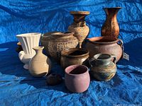 Front angle view of assorted flower pots and vases on blue tarp