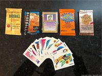 Photo of trading card packs and assorted loose cards including baseball and basketball themes.