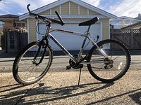 Side view of the bike showing silver frame, black details, and front suspension fork.