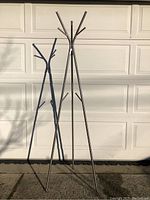 Full view of the metal coat stand showing its tripod leg design and height.