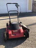 Red and black Black & Decker electric lawnmower showing front view with power cord and wheels.