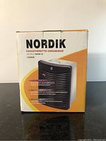 Front view of Nordik ceramic heater box showing model number HP815 and power rating 1500W with feature highlights in French.