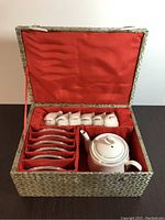 Tea set inside decorative gift box with red fabric lining includes six cups, six saucers, and one teapot.